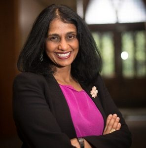 woman with black hair, brown eyes, wearing black suit jacket and pink blouse
